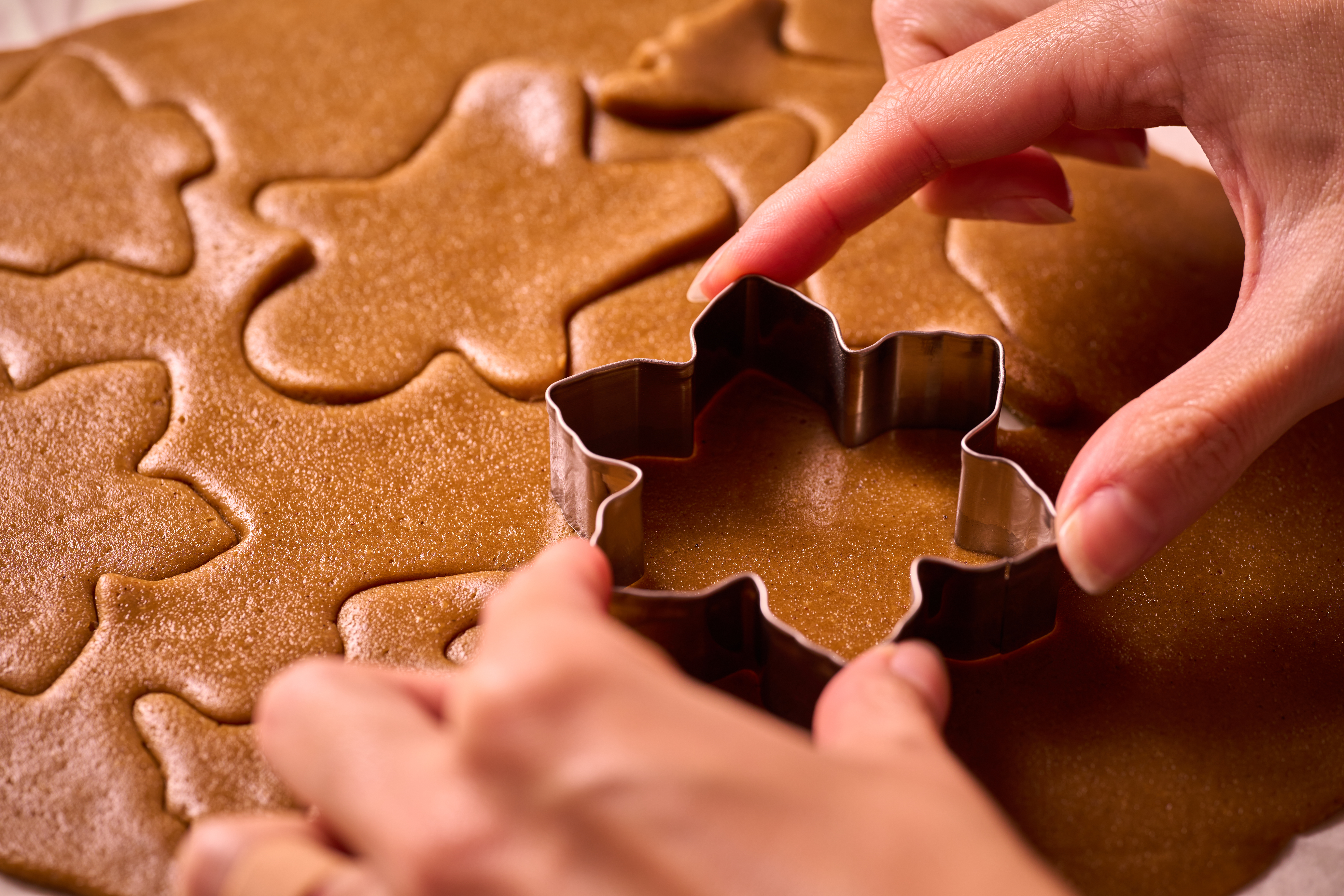 Person cutting out cookies with cookie cutter.